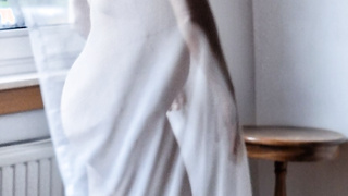 Frau am Fenster in Gardine gehüllt